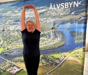 Bild på Ylva när hon gör en yogaövning framför en bild på Älvsbyn.